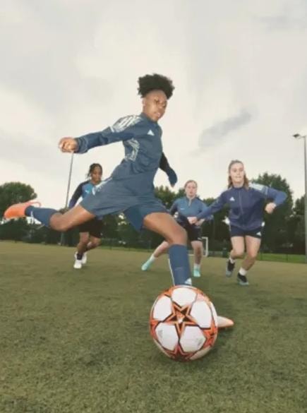Young female athlete kicking soccer ball in action
